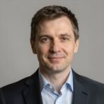 Портрет уверенного российского бизнесмена с дружелюбным взглядом на размытом нейтральном фоне в студии